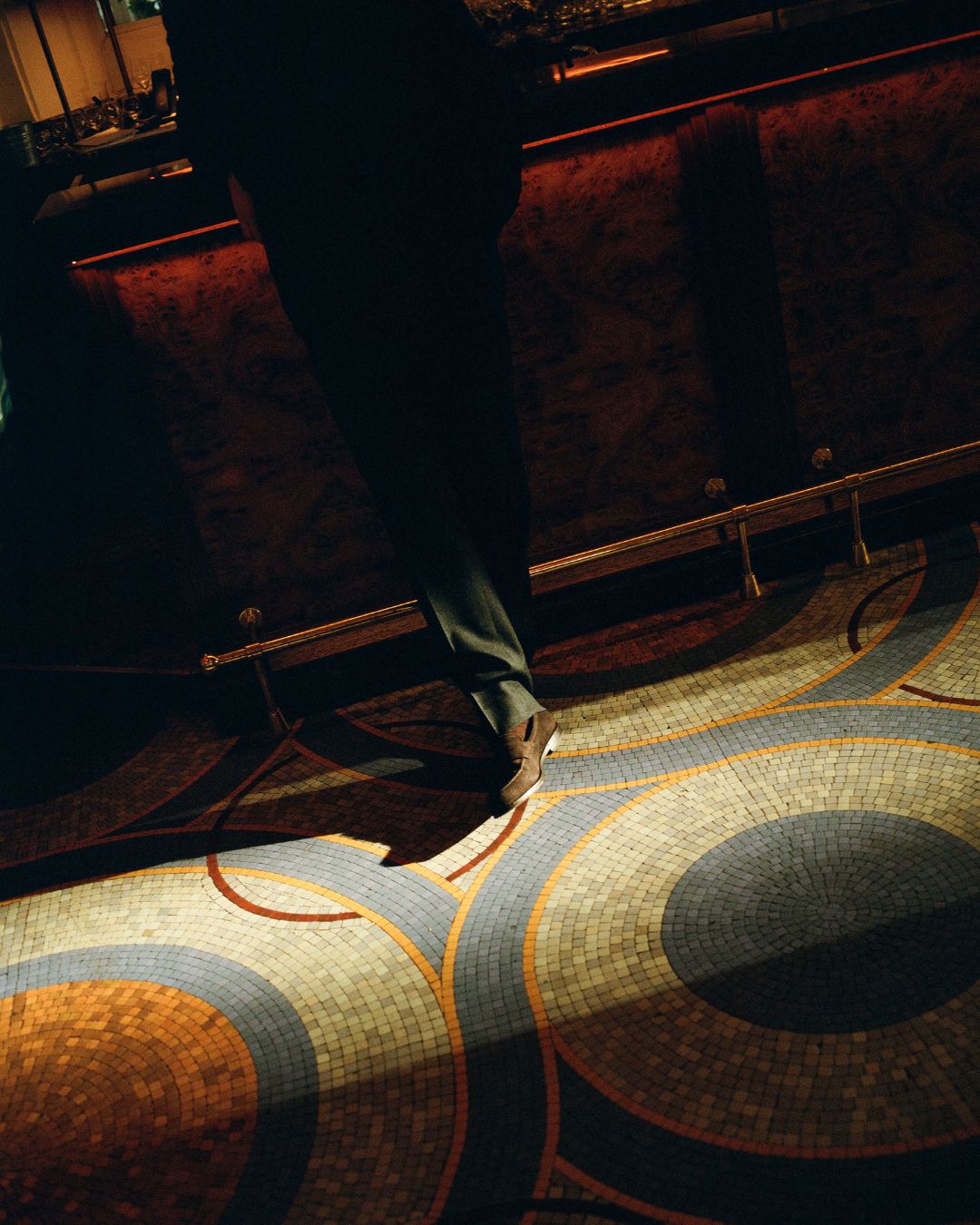 Person walking on a patterned carpet in a dimly lit room