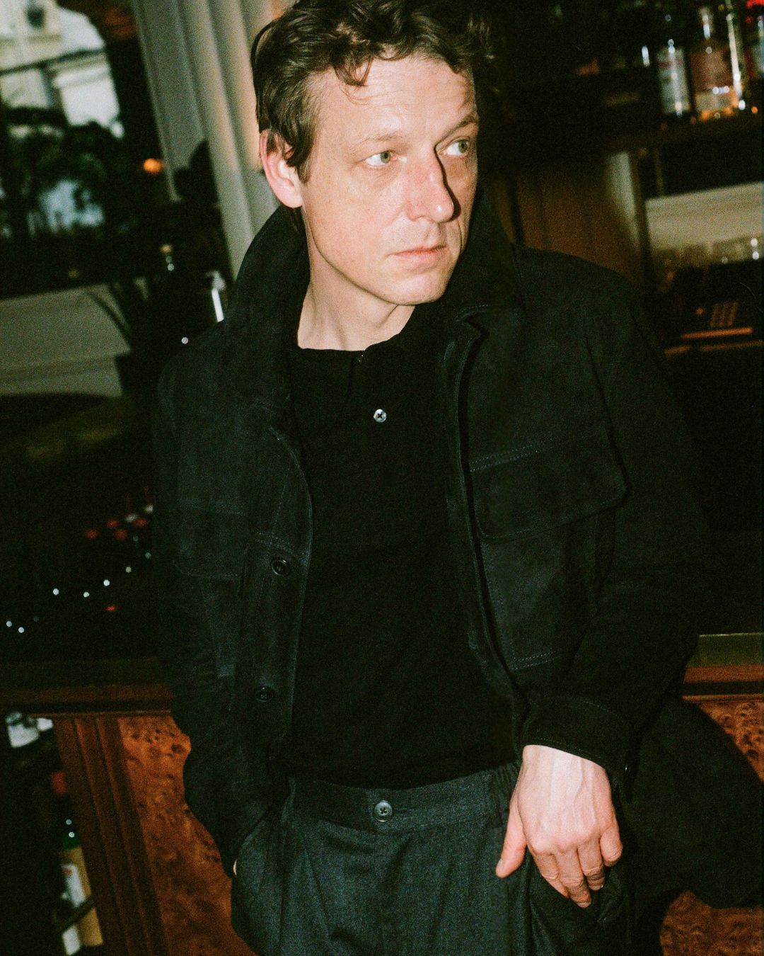 Man in a dark jacket standing in a bar setting
