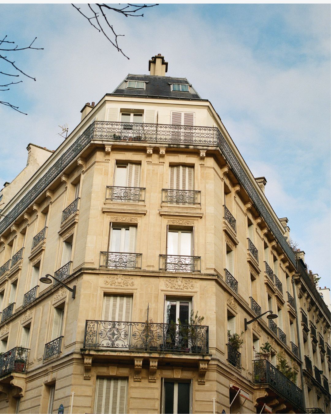 Corner of a historic building with architectural details against a blue sky.