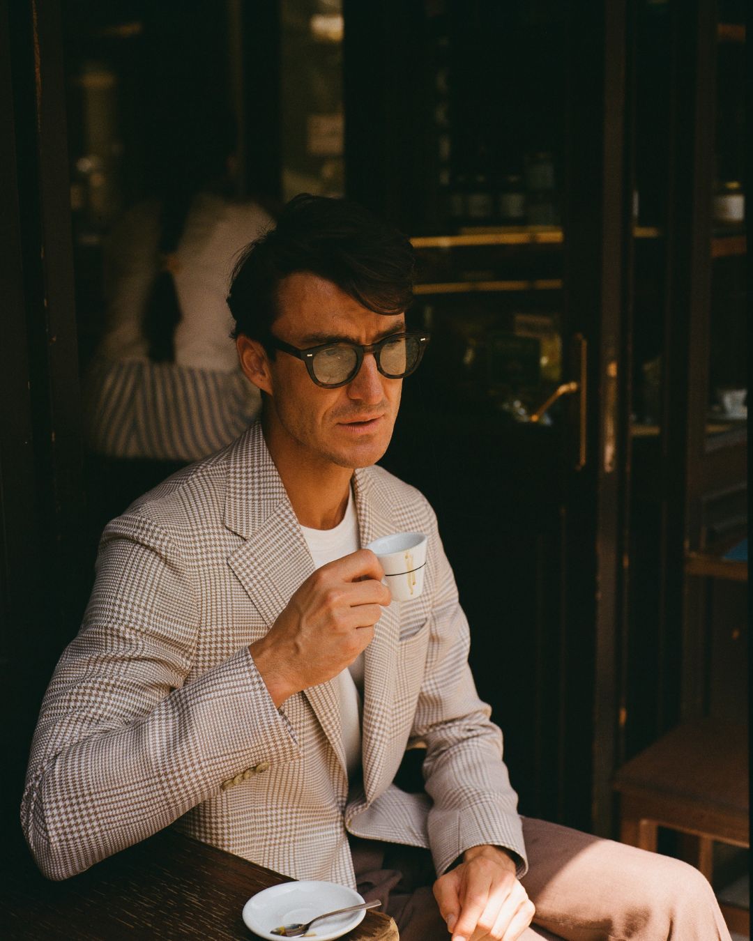 Man in a suit holding a cup in a dimly lit room